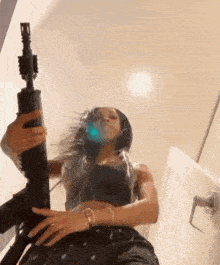 a woman is holding a gun in her hand while standing next to a door .