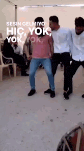 a group of men are dancing in front of a sign that says ' senin gelmiyo hic yok yok yok '