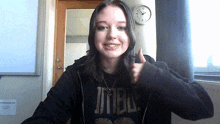 a girl wearing a black shirt that says jtbn gives a thumbs up