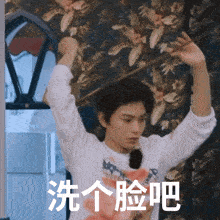 a man with chinese writing on his shirt holds his hands up