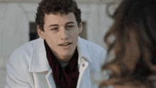 a young man with curly hair is talking to a woman .