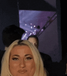 a woman with blonde hair is making a funny face in a dark room