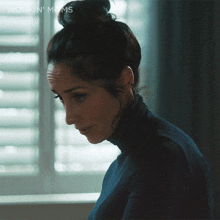 a woman with a bun on her head is sitting in front of a window with the words workin ' mums written below her