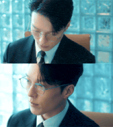 a man in a suit and tie wearing glasses is looking down
