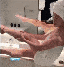 a woman in a bathtub with a towel wrapped around her head is applying lotion to her leg