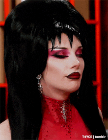 a drag queen wearing a black wig and a red dress