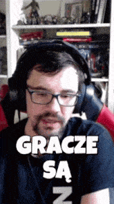 a man wearing glasses and headphones is sitting in front of a shelf and says gracze sa n