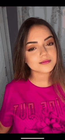 a woman wearing a pink t-shirt with the word tu on it .