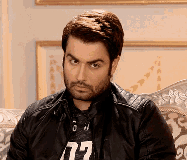 a man wearing a black leather jacket and a t-shirt that says 77