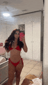 a woman in a red bikini is taking a selfie in a mirror