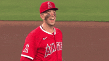 a baseball player wearing a red uniform with angels on the front