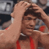a man in a red shirt is holding his head