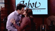 a man and a woman kiss in front of a tabot tics sign