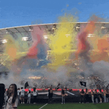 a group of people standing in a stadium with smoke coming out of it