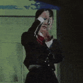 a woman in a black suit and red bow tie is standing in a bathroom .