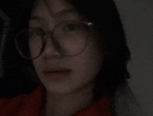 a woman wearing glasses and a red shirt is looking at the camera