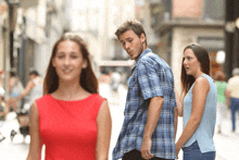 a man in a plaid shirt is walking down the street with a woman in a red dress behind him