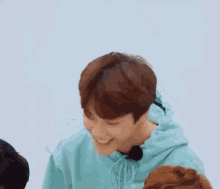 a young man in a blue hoodie is smiling while sitting next to another young man .