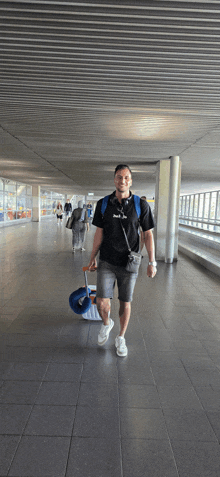 a man wearing a black shirt with the word puma on it walks through an airport