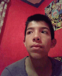 a young man is looking at the camera with a red wall behind him