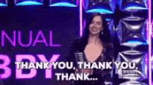 a woman is standing in front of a thank you sign .
