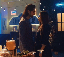 a man and woman are kissing in front of a sign that says open class