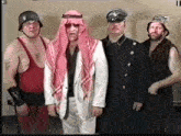 a group of men are standing next to each other and one of them is wearing a red tank top