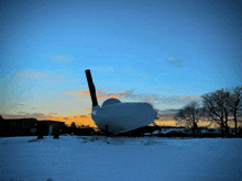 a large white object is sitting in a snowy field