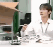 a man is sitting at a table holding a cup of coffee and a microphone .