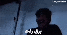 a man is screaming in a dark room in a video with arabic writing .