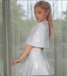 ariana grande is wearing a white dress and a white cape .