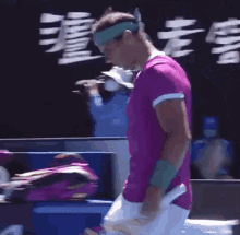 a man in a pink shirt holds a tennis racquet in front of a sign that says 15