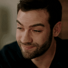 a man with a beard is smiling and looking to the side