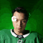 a man wearing a green nhl jersey with the letter g in front of his eyes