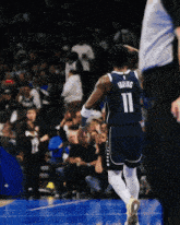 a basketball player with the number 11 on his back walks on the court