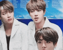 a group of three young men are standing next to each other and looking at the camera .