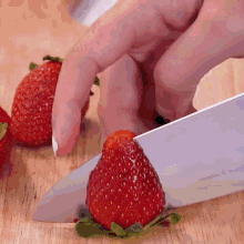 a person is cutting strawberries on a cutting board