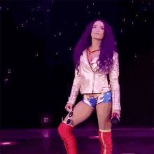 a woman with purple hair and red boots is standing on a stage holding a microphone .