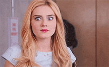 a woman with blonde hair is making a funny face while looking at the camera .