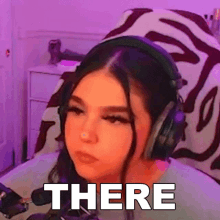 a girl wearing headphones is sitting in front of a microphone and making a face .
