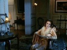 a woman is sitting in a chair reading a magazine
