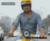 a man wearing a yellow helmet is riding a scooter with the website starttamilchat.in in the background