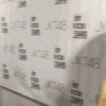 a woman in a yellow dress is standing in front of a wall with kt48 written on it .