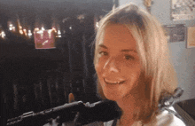 a woman is smiling in front of a microphone with a candle in the background