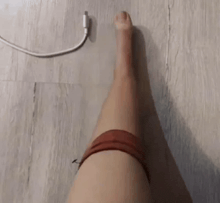 a person 's leg is standing on a wooden floor next to a charger .