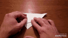 a person folding a piece of paper with the words made in animotica below