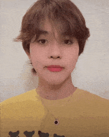 a young man wearing a yellow shirt with chickens on it and a necklace