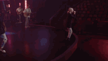 a woman singing into a microphone with her hand up in the air