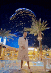 a man in a bathrobe is dancing in front of a large building that has the word container on it