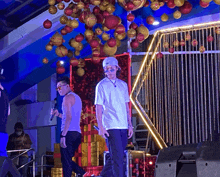 two men stand on a stage in front of a christmas decoration